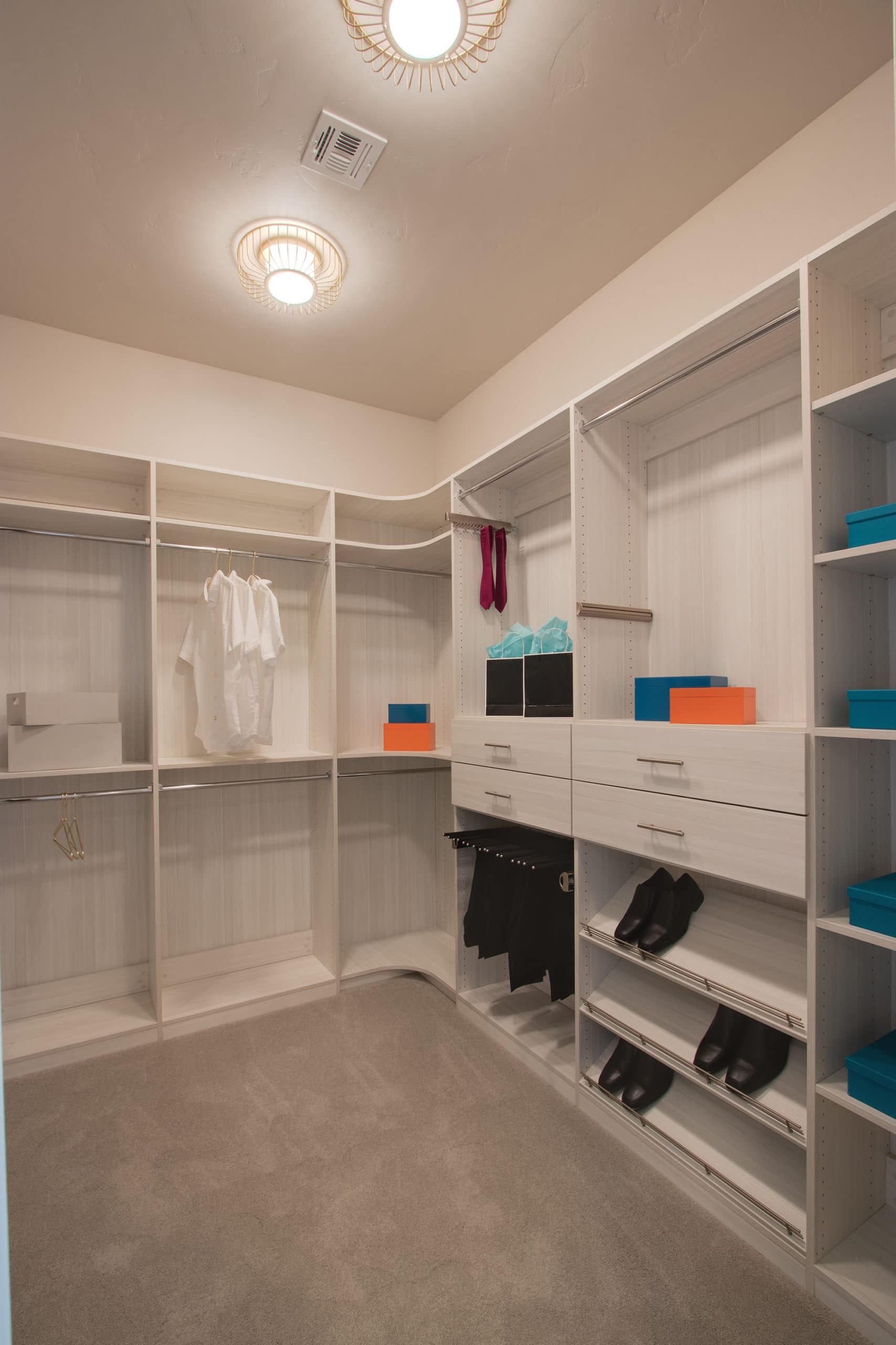 vertical image of a white walk in closet for men with double hang shelves shoe shelves and cabinet
