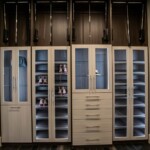 Two luxury shoe racks rest alternately with the clothes shelves in classy glass doors in a master bedroom with his and hers closets in Las Vegas