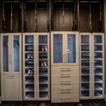 Two luxury shoe racks rest alternately with the clothes shelves in classy glass doors in a master bedroom with his and hers closets in Las Vegas
