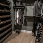 View of the wooden shoe shelves and cabinet of the His and Hers walk in closet.