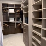 View of the men's closet with double hang shelves, soft close cabinet, and shoe shelves.