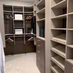 View of the men's closet with double hang shelves, soft close cabinet, and shoe shelves.