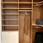 Her side of the closet with corner shelves and rods, drawers, and a hidden hamper.