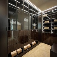 This primary walk in closet has drawers with flat faces that meet at the edges with finger-pull handles, keeping the overall look of the closet sleek.