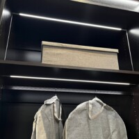 This walk in closet features long hang shelves and a storage shelf. Both are lit for your convenience.