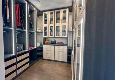 Light and dark floor to ceiling walk-in closet with LED's, glass cabinets and pulldown rods
