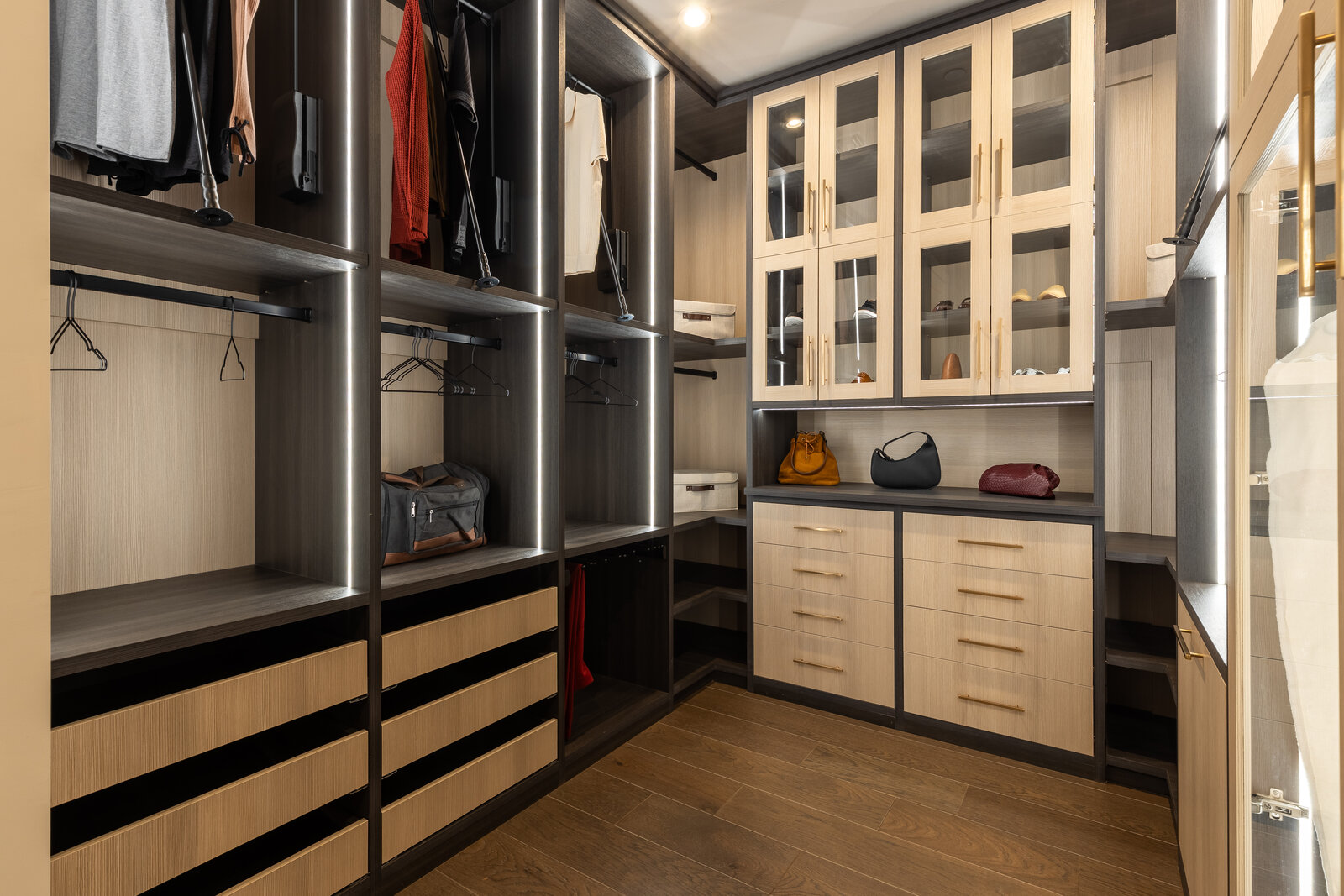 Custom walk-in closet with dark frame glass upper cabinets