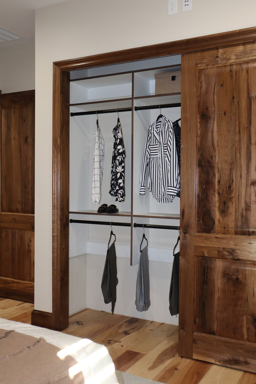 Custom reach-in closet with sliding wood doors, staged with clothing