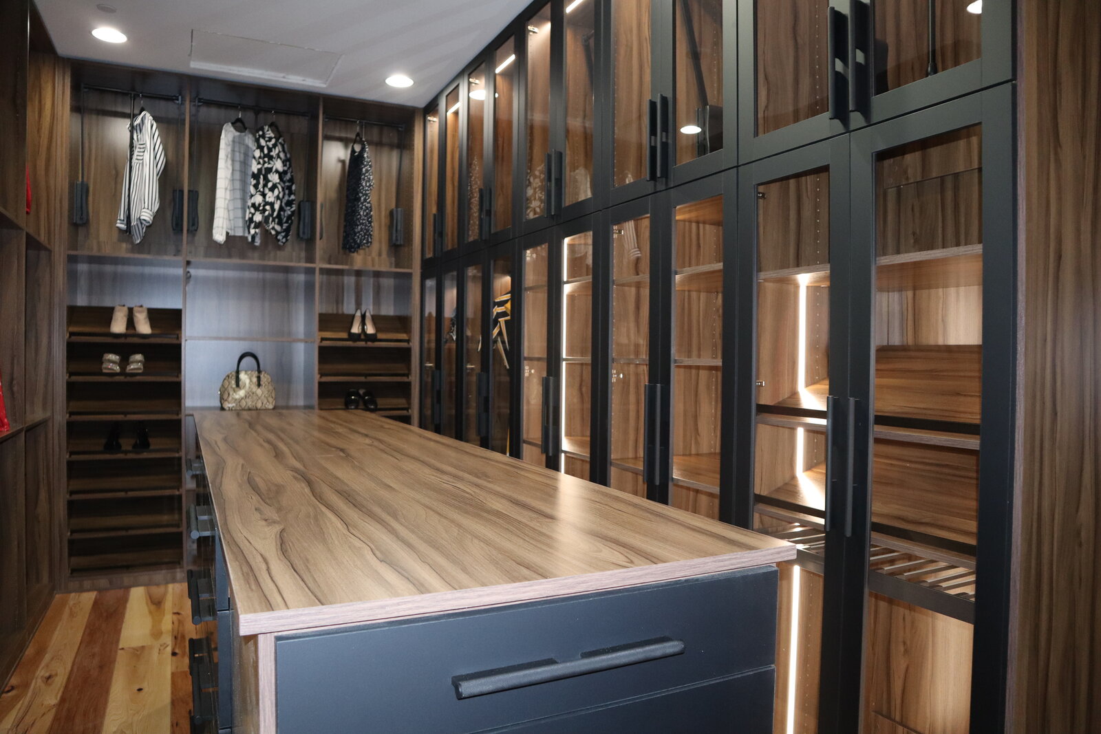 Staged custom walk-in closet with island and lit glass wardrobes, Las Vegas